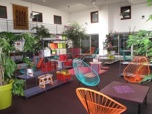 een kamer met kleurrijke stoelen, tafels en planten bij Hotel Aurena in Aurillac