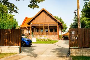 a house with a gate and a blue car in front at Bor, Villa, Sóstó in Nyíregyháza