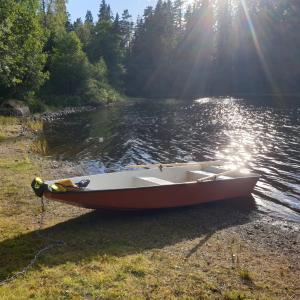 a boat sitting on the shore of a lake at Cabin near lake and beautiful nature reserve. in Bodafors
