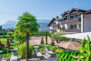 a resort with a palm tree and tables and umbrellas at Hotel Christine in Gargazzone