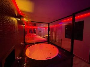 a large bath tub in a room with red lights at Adrenalina Motel Itaquera - Arena Corinthians in São Paulo