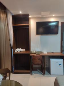 a room with a desk with a television on a wall at Hotel Universal in Santarém