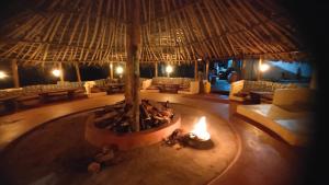 an outdoor area with a fire pit with a large straw umbrella at StoneAge Resort Sakleshpur in Sakleshpur