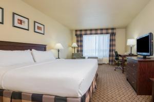 Holiday Inn Express Hotel & Suites El Dorado, an IHG Hotel في El Dorado: غرفة فندقية بسرير وتلفزيون بشاشة مسطحة