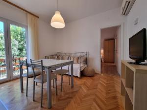 a dining room with a table and chairs and a tv at Apartment Duce 2821c in Duće