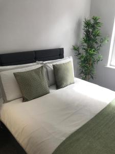 a large white bed with pillows and a plant at 1Bed Golfhill Cottage in Dunblane