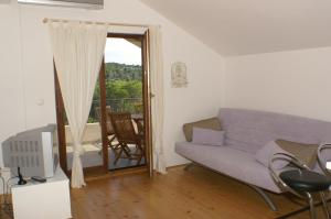 Una sala de estar con un sofá y un balcón. en Seaside family friendly house with a swimming pool Cove Osibova, Brac - 2837, en Milna