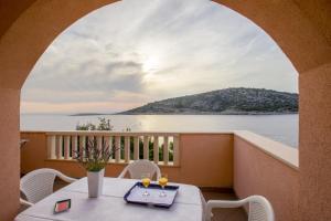 a balcony with a table and chairs and a view of the water at Apartments by the sea Razanj, Rogoznica - 2970 in Rogoznica