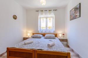 a bedroom with a bed with two pillows and a window at Apartments by the sea Sumartin, Brac - 2952 in Sumartin