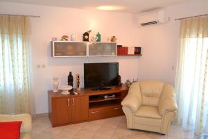 a living room with a television and a chair at Apartments with a parking space Postira, Brac - 2948 in Postira