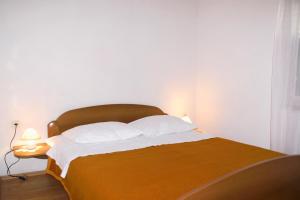 a bed with a wooden headboard and white pillows at Apartments and rooms with parking space Bol, Brac - 2926 in Bol