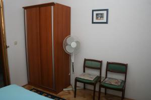 a bedroom with two chairs and a fan and a closet at Double Room Sutivan 2943b in Sutivan