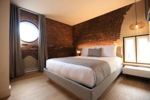 a bedroom with a large bed and a brick wall at Le 31 McMahon - Par Aneyro in Quebec City