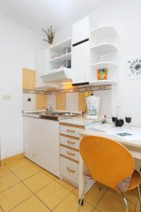 a kitchen with white cabinets and a orange chair at Apartment Postira 2913b in Postira +17 photos