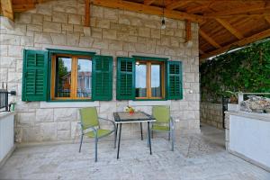 a patio with a table and chairs and green shutters at Apartment Postira 2913b in Postira