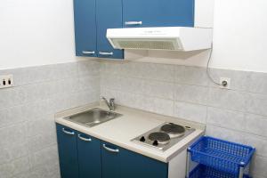 eine Küche mit einer Spüle, einem Herd und blauen Schränken in der Unterkunft Apartments with a parking space Bol, Brac - 2879 in Bol