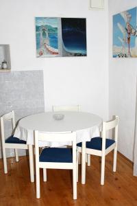 einen weißen Esstisch und Stühle mit Gemälden an der Wand in der Unterkunft Apartments with a parking space Bol, Brac - 2879 in Bol