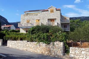 a stone house with a stone wall and a stone fence at Apartments with a parking space Bol, Brac - 2900 in Bol