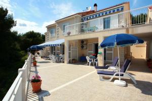 a house with chairs and umbrellas on a patio at Apartments by the sea Sumartin, Brac - 2940 in Sumartin