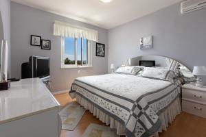 a white bedroom with a bed and a television at Apartments by the sea Sumartin, Brac - 2940 in Sumartin