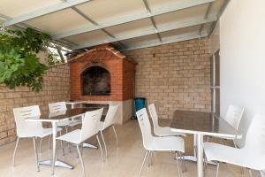 een patio met tafels en witte stoelen en een bakstenen oven bij Apartments by the sea Duce, Omis - 2992 in Dugi Rat