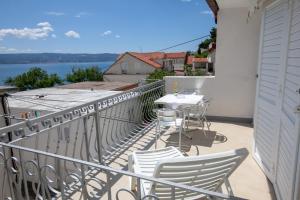 een balkon met een tafel en stoelen en uitzicht op het water bij Apartments by the sea Duce, Omis - 2992 in Dugi Rat