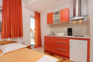 a small kitchen with red cabinets and a sink at Apartments with parking space Vodice - 2995 in Vodice