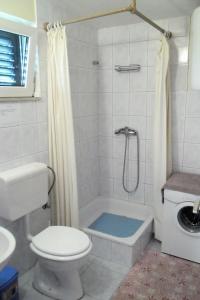 a white bathroom with a toilet and a shower at Apartments by the sea Splitska, Brac - 2923 in Postira