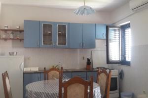 Apartments and rooms by the sea Sutivan, Brac - 2943 في سوتيفان: مطبخ مع دواليب زرقاء وطاولة مع كراسي
