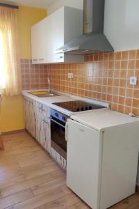 a kitchen with white cabinets and a stove top oven at Apartments with a parking space Bol, Brac - 2890 in Bol