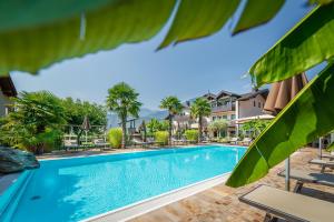 een zwembad in een resort met tafels en stoelen bij Hotel Christine in Gargazzone