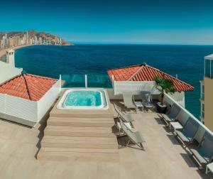 a swimming pool on a balcony with chairs and the ocean at Gastrohotel Boutique RH Canfali in Benidorm