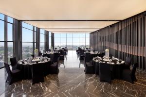a banquet hall with tables and chairs and large windows at Hotel Aruss Semarang in Semarang