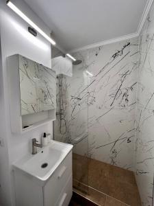 La salle de bains blanche est pourvue d'un lavabo et d'une douche. dans l'établissement Ancodirect Apartments, à Rădăuţi
