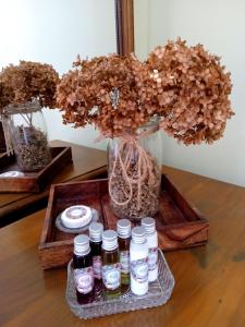 a tray with four bottles of essential oils and a vase with flowers at La Belle Vienne in Exideuil