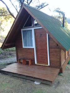eine kleine Holzhütte mit einer Veranda und einem Fenster in der Unterkunft Chalés Snow in Urubici