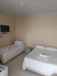 a hotel room with two beds and a tv at Hospedagem Quinta do Correia in Penha