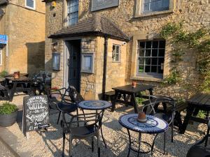 a patio with tables and chairs in front of a building at The Mousetrap Inn in Bourton on the Water