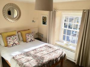 a bedroom with a bed with a mirror and a window at The Mousetrap Inn in Bourton on the Water