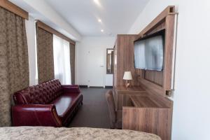 a hotel room with a couch and a flat screen tv at Hotel Cataleya in Almere
