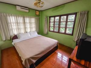 a bedroom with a bed with green walls and windows at Sabaydee Guesthouse in Ban Houayxay