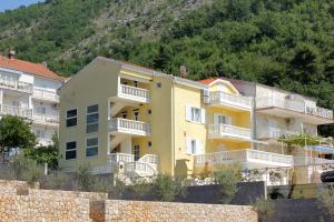 un bâtiment jaune avec des balcons blancs en face d'une montagne dans l'établissement Apartments with a parking space Slano, Dubrovnik - 3183, à Slano