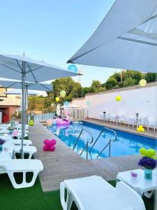 a swimming pool with white tables and chairs and an umbrella at Il Castello in Terzigno
