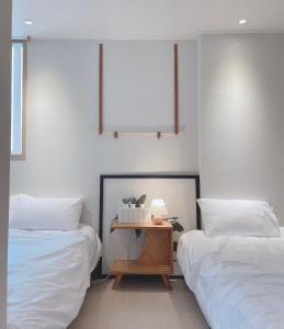 a bedroom with two beds and a table with a lamp at Well Plus Guest House in Seoul
