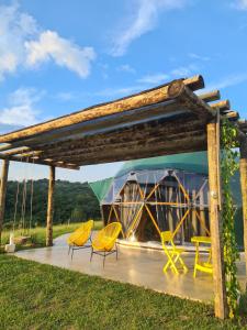 a wooden pergola with yellow chairs and a tent at Domo da Cuesta - Glamping com vista para a montanha in Bofete