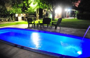 Los Olivos Loft في روزاريو: مسبح في الليل مع كراسي وطاولة