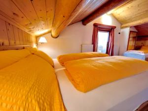 two beds in a room with yellow sheets at Garni Francescato in Livigno