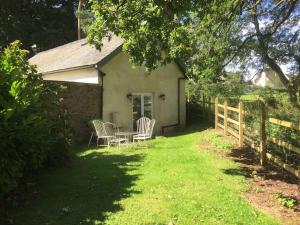 a house with two chairs and a table in the yard at St Michaels Coach House in Crediton