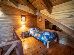 um quarto com uma cama num chalé de madeira em Hosteria Pichi Rincon em Villa La Angostura