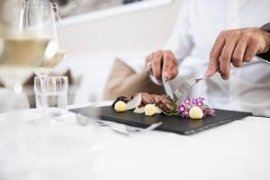 a person cutting up food on a cutting board at Classic Hotel Am Stetteneck in Ortisei